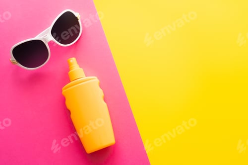 Preview: Top view of sunglasses and sunblock on pink and yellow background
