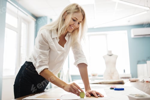 Preview: A smart-looking blond woman is lining a sewing cutting-out with a piece of soap. Fasion, tailor'