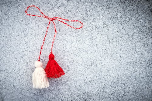 Preview: martenitsa. Bulgarian Symbols of spring. Red and white tassels of threads on the ground covered with