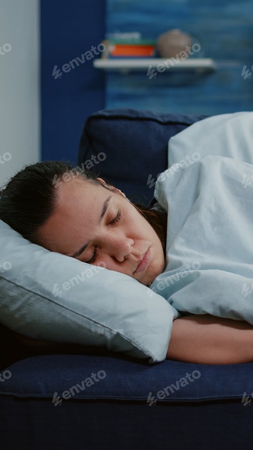 Preview: Close up of ill adult laying wrapped in blanket on sofa