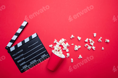 Preview: Clapperboard and pop corn on red color background, top view