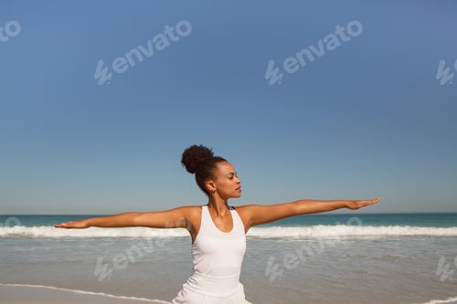 Preview: Front view of beautiful African american woman doing yoga at beach in the sunshine
