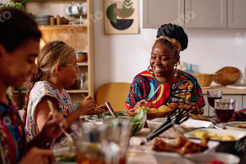 Preview: Cheerful young woman in exotic attire sitting by served festive table