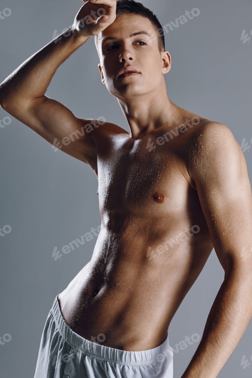 Preview: guy bodybuilder with pumped up arm muscles on gray background cropped view close-up