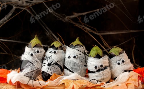 Preview: Halloween background. Spooky eggplant wrapped in medical bandages on a wooden table.Halloween food