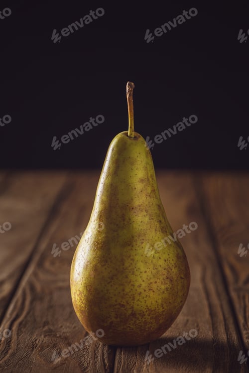 Preview: close-up shot of ripe yellow pear on rustic wooden table on black