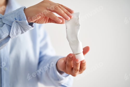 Preview: Hands in a blue shirt hold a tube of cream.