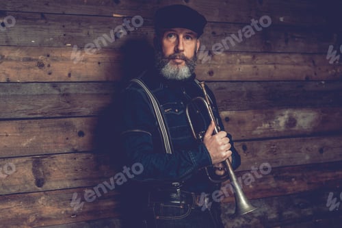 Preview: Half Body Shot Of An Adult Male Musician Wearing Black Clothing With Ivy Cap Holding A Trumpet