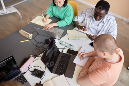 Vista previa: Vista panorámica de estudiantes interculturales que toman notas y utilizan dispositivos móviles