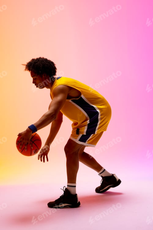 Preview: Image of biracial basketball player bouncing basketball on pink to orange background