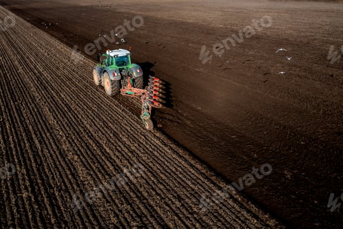 Preview: Aerial view directly above a tractor ploughing a fertile field with scavenging birds in flight