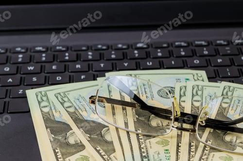 Preview: American twenty dollar banknotes, glasses on the keyboard laptop money on the Internet, freelancer