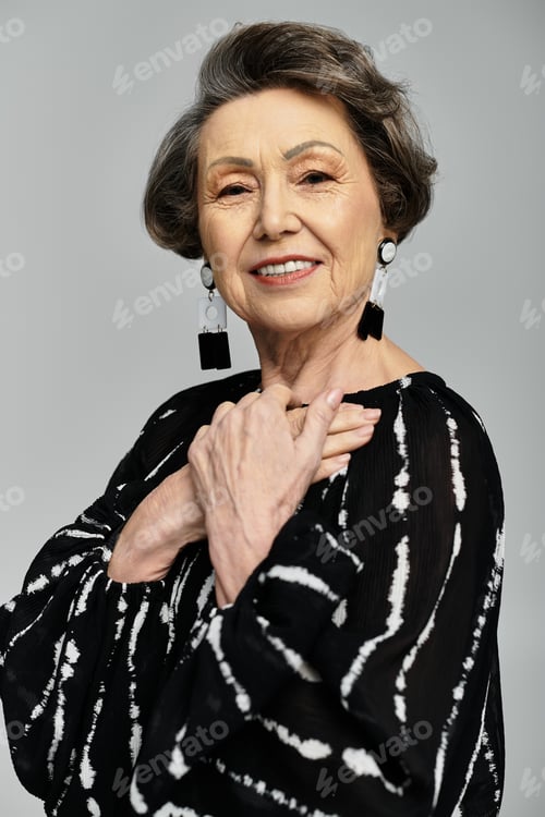Preview: A beautiful woman exudes elegance in trendy attire against a grey backdrop.