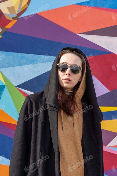 Preview: A young creative woman stands against the backdrop of a bright, colorful, multi-colored wall.