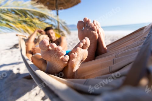 Preview: Caucasian couple lying on a hammock at the beach.