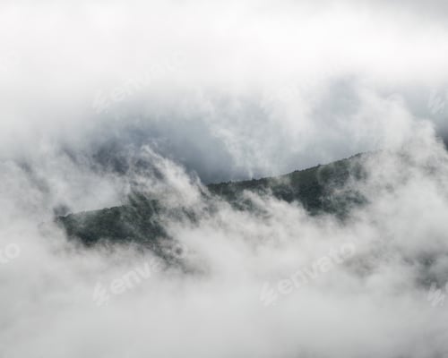Preview: A window opens amongst the dense fog revealing forested slopes