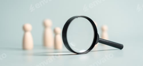 Preview: A magnifying glass is on a table with a group of wooden figures. The figures are arranged in a row.