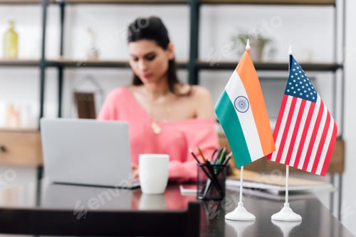 Preview: selective focus of american and indian flags on table and girl studying with laptop