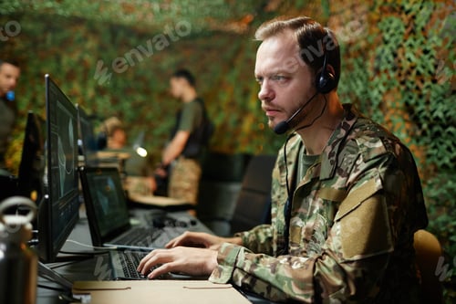Preview: Young serious male operator with headset looking at computer screen