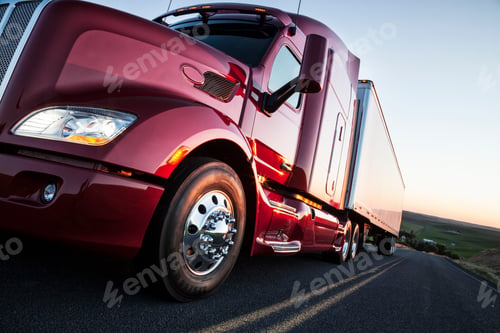 Preview: Front to rear low angle view of the cab of a commercial truck on the highway late in the day.