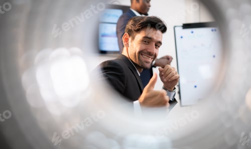 Preview: Portrait of a smiling young businessman showing thumbs up while working in office