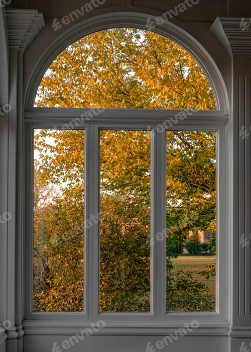 Preview: Vertical shot of an arched modern window with a beautiful autumn scene