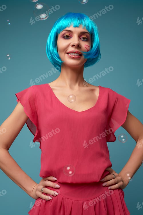 Preview: Beautiful young woman with blue wig and bright make-up in soap bubbles. Fashion model girl with