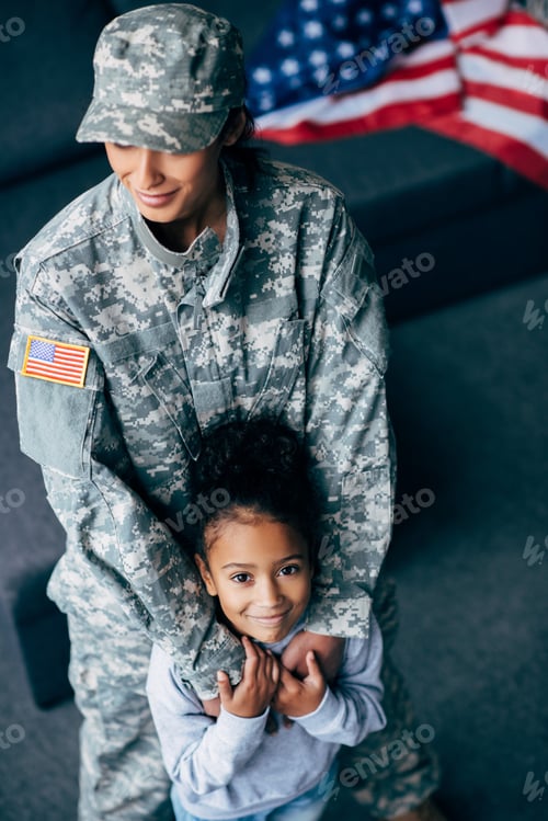 Preview: african american daughter and mother in military uniform at home with american flag on background