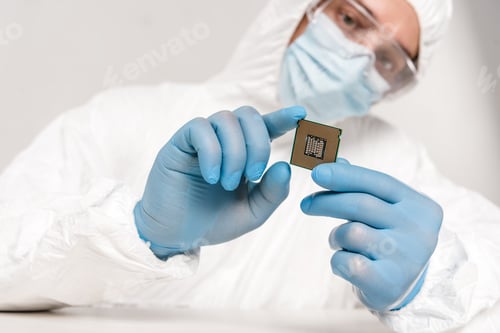 Preview: selective focus of microprocessor in hands of scientist in googles on grey background