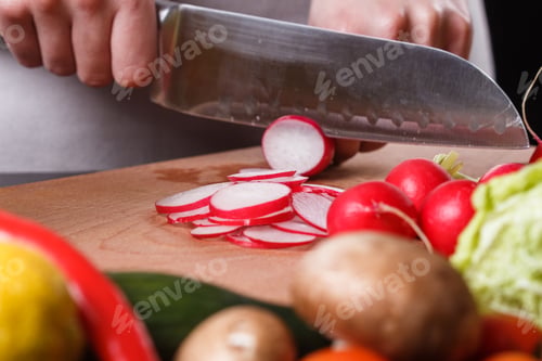 Preview: young woman in a gray apron cuts a radish