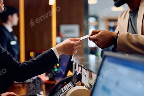 Preview: Close up of hotel receptionist giving room cardkey to black hotel guest.