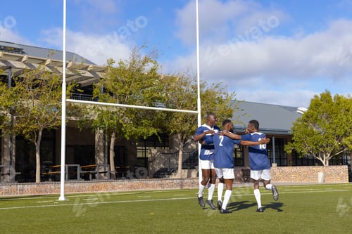 Preview: Three African American young male athletes celebrating on a rugby field outdoors