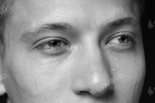 Preview: Sad man crying on dark background, closeup. Black and white effect
