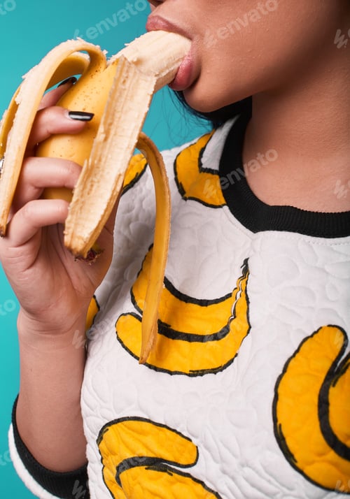 Preview: Fashion Swag Close-Up Portrait Of Beautiful Elegant Asian Woman Eating Banana On Bright Background
