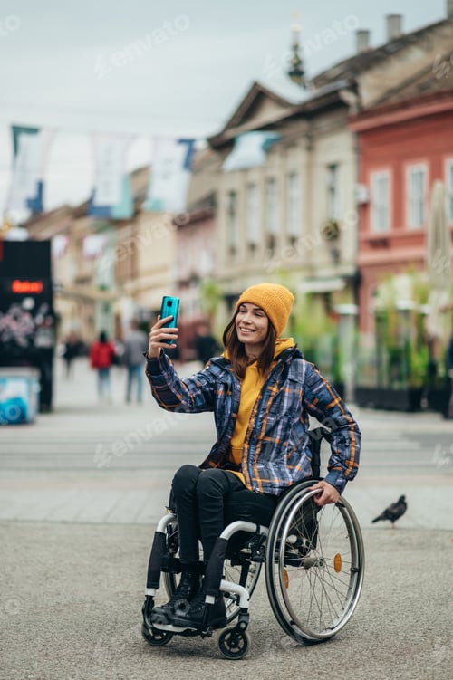 Preview: Woman with disability taking a selfie with her smartphone while out in the city