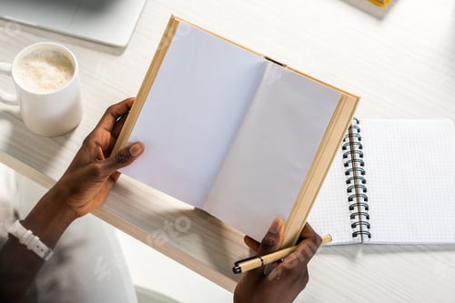 Preview: partial view of african american with book at table at home office