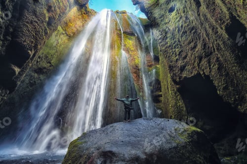 Preview: Traveler stunned by Gljufrabui waterfall cascade in Iceland.