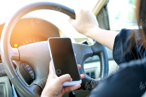 Preview: Woman using a smartphone while driving.