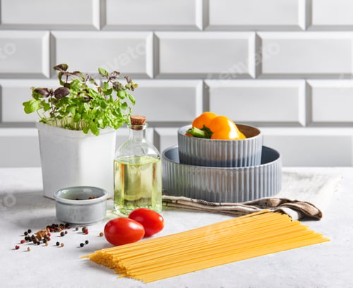 Preview: Raw spaghetti with tomatoes, basil, pepper and olive oil on a white brick background.
