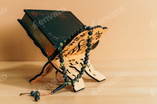 Preview: Closeup shot of the Quran with a rosary on wooden stand