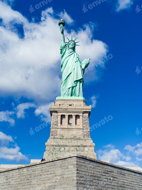 Preview: Low angle vertical view of the Statue of Liberty National Monument under blue sky in New York