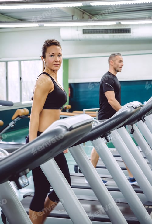 Preview: Woman with earphones training over a treadmill