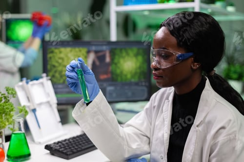 Preview: African american biologist researcher holding medical test tube with green solution