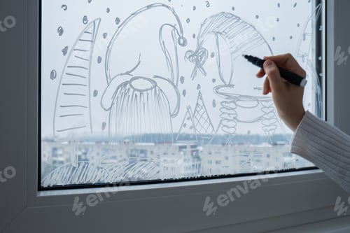 Preview: Sustainable responsible holiday decor. Female hand painting gnomes painted on window glass indoor at