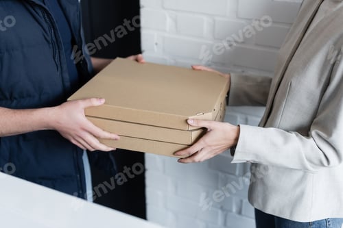 Preview: Cropped view of businesswoman and courier holding pizza boxes in office