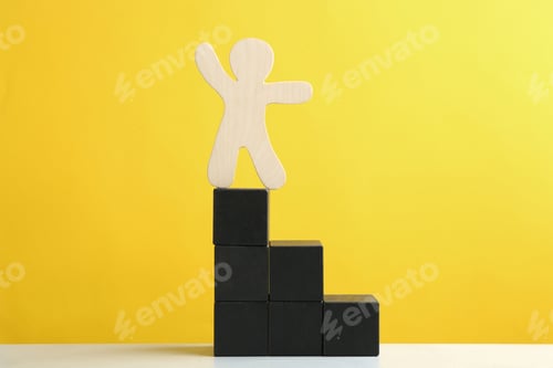 Preview: Wooden human figure on top of block staircase against yellow background. Career promotion concept