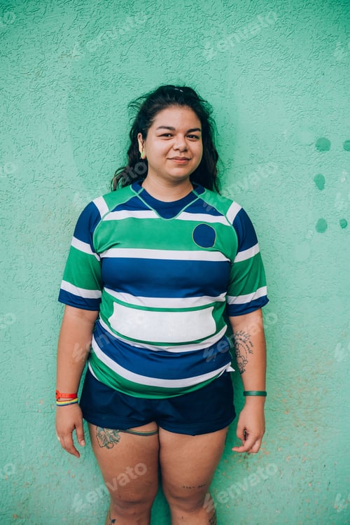 Preview: Confident young woman posing in front of a green wall