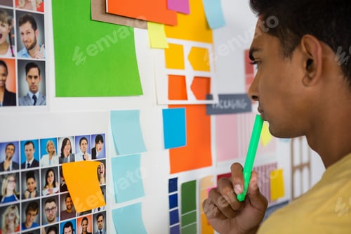 Preview: Thoughtful man looking at sticky notes in office