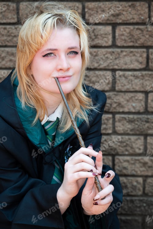 Preview: Blonde Caucasian female cosplayer dressed as a wizard with a magic wand