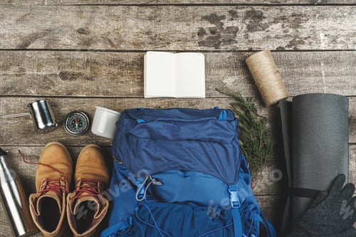Preview: Backpack and hiking equipment on wooden background, top view
